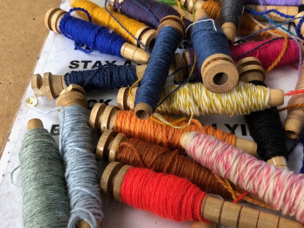 a pile of small spools of different coloured threads on a table