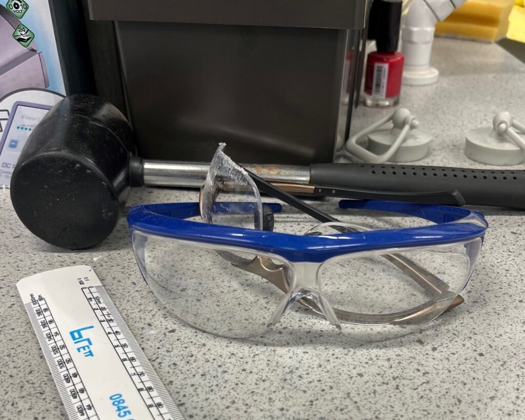 Lab counter with black mallet, safety goggles, a ruler, and nail polish ( which is good for marking lab glassware).