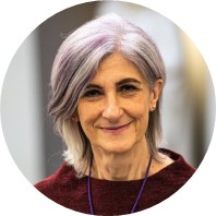 White woman with grey hair dyed slightly purple.