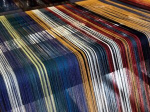 A loom with a variety of colourful threads stretching away into the loom.