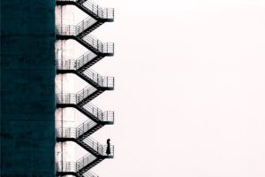 Illustration of a person climbing up a tall staircase on the outside of a building