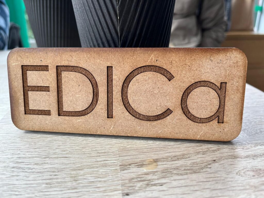 EDICa's name engraved by laser onto a piece of MDF, sitting on a table