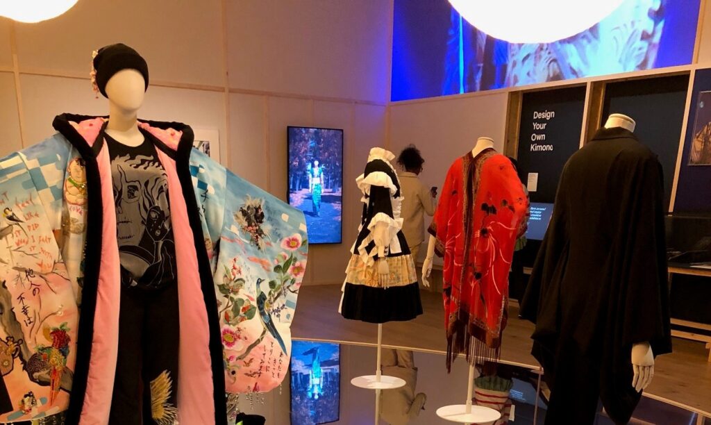 A museum hall with various exhibits of mannequins in fashionable outfits inspired by the kimono. The floor is a mirror.